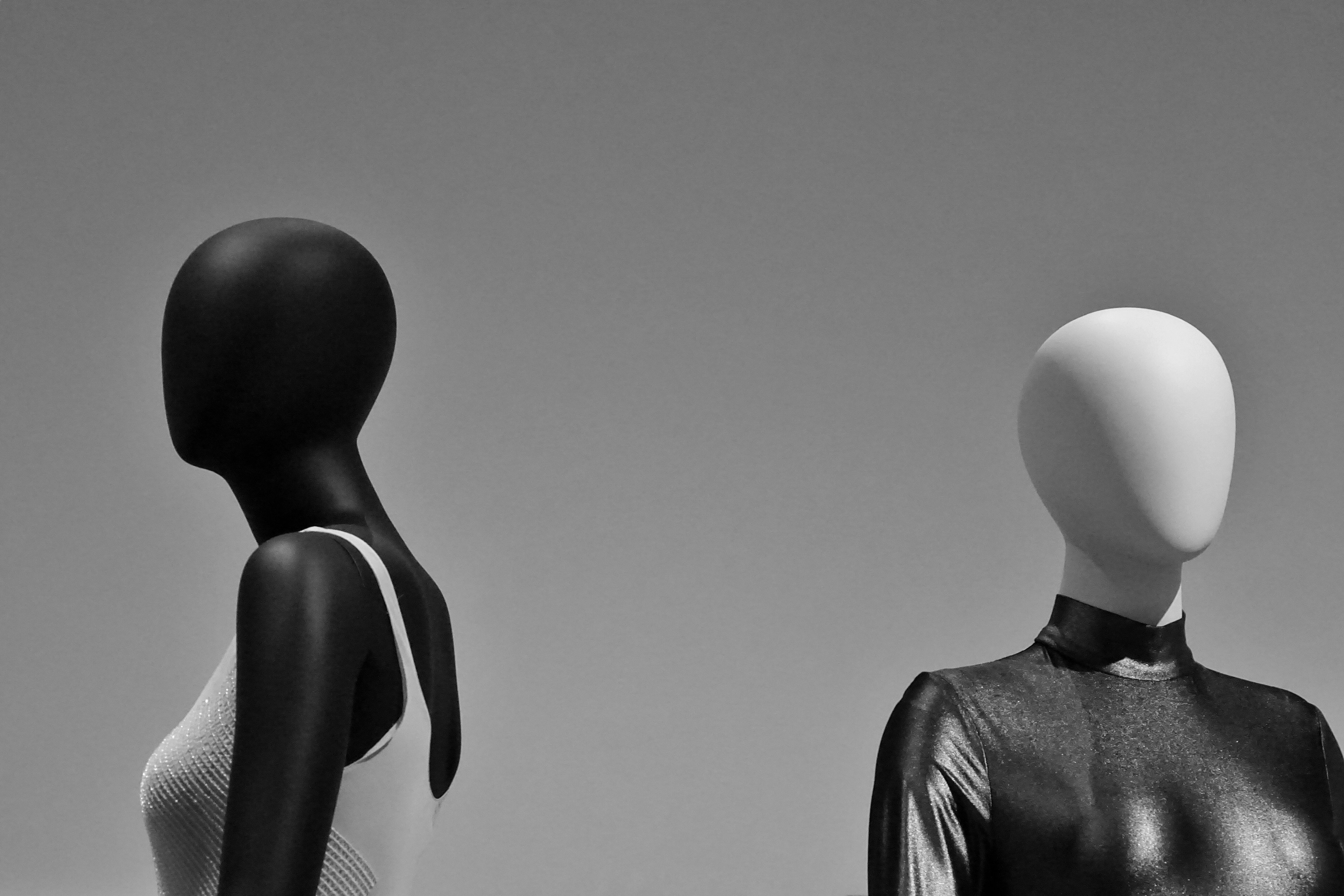 Two mannequins in organic-looking garments against a pale studio wall