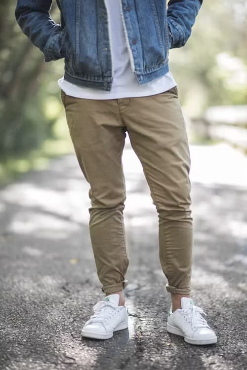 Khaki slim chino trousers worn with white sneakers and a denim jacket outdoors