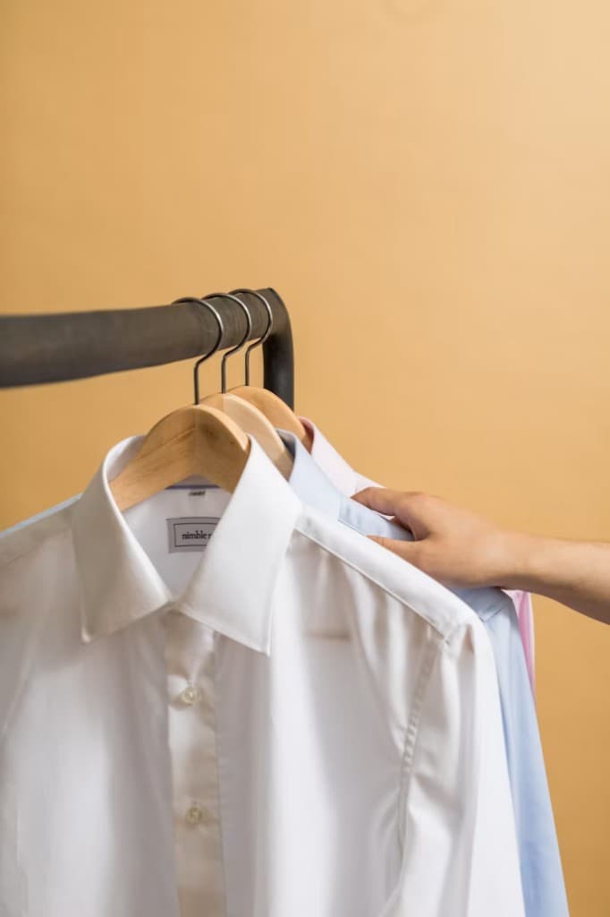 Hanging organic cotton crew-neck t-shirts in bone, bordeaux, black, and tan on steel hooks